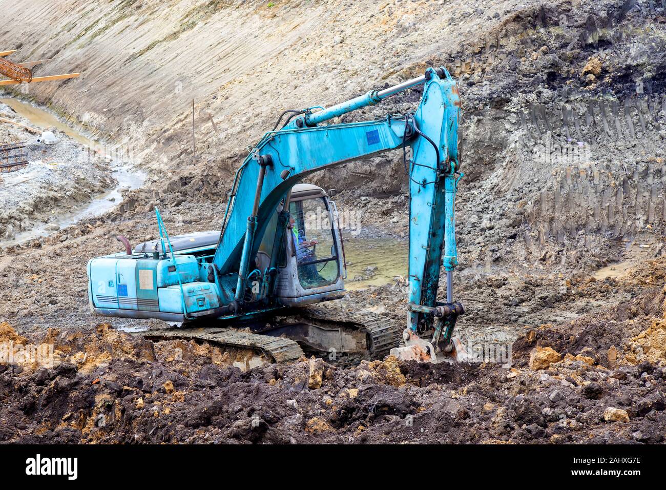 Blue excavator digging foundation at construction site. Excavator