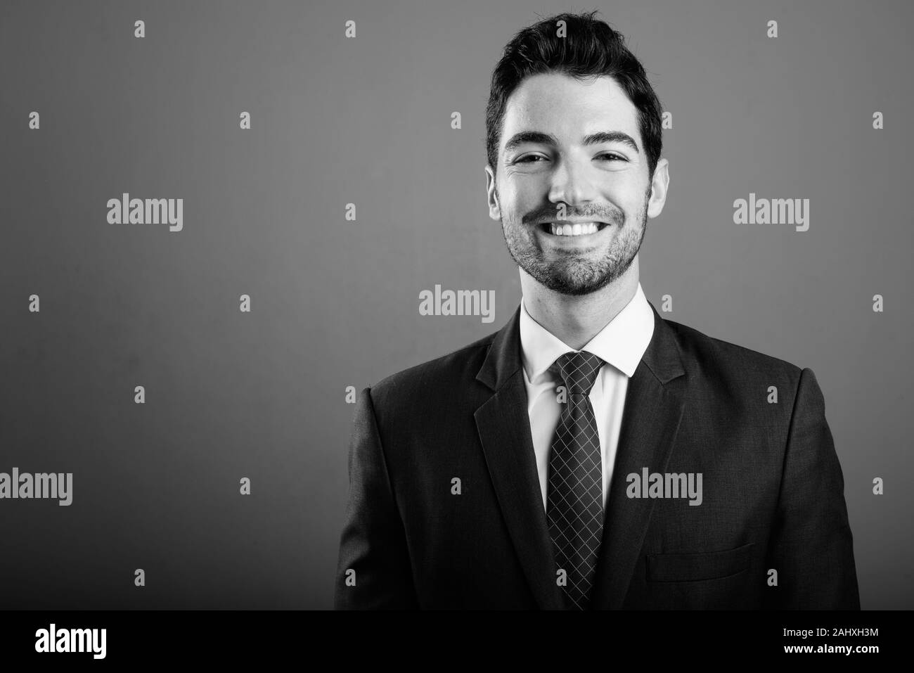 Young handsome businessman in suit against gray background Stock Photo ...