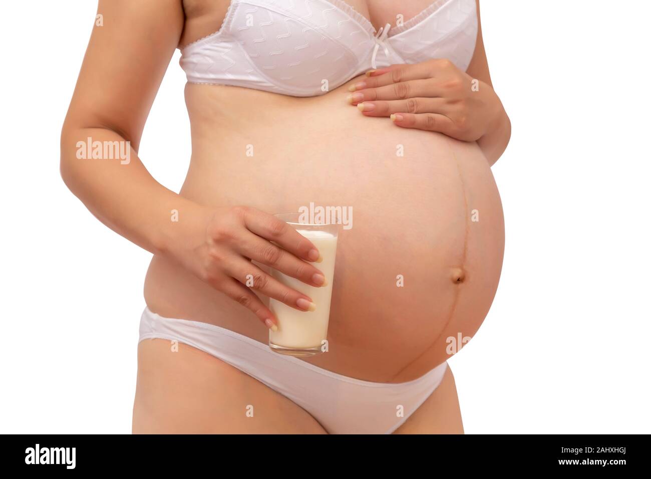 Pregnant woman holding glass of milk at her tummy. Pregnan concept: healthy nutrition during pregnancy. Stock Photo