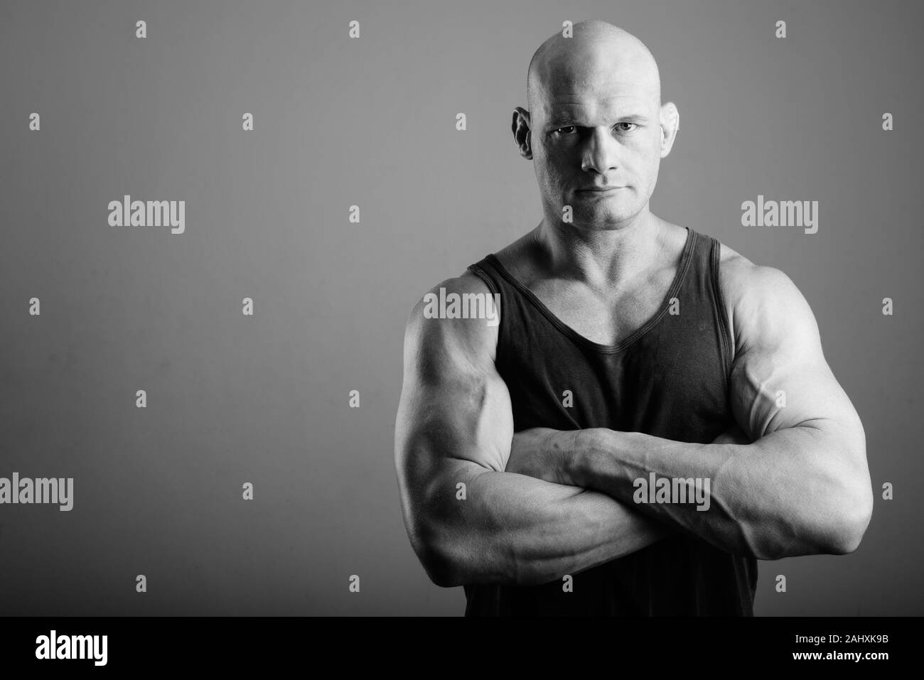 Bald muscular man wearing tank top against gray background Stock Photo