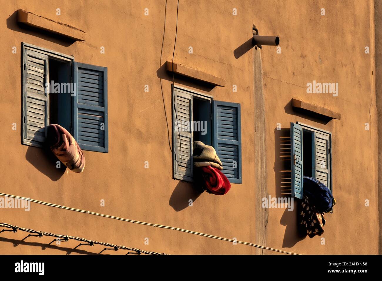 Bedcover hanging out of windows of an house in the medina of Tiznit Stock Photo