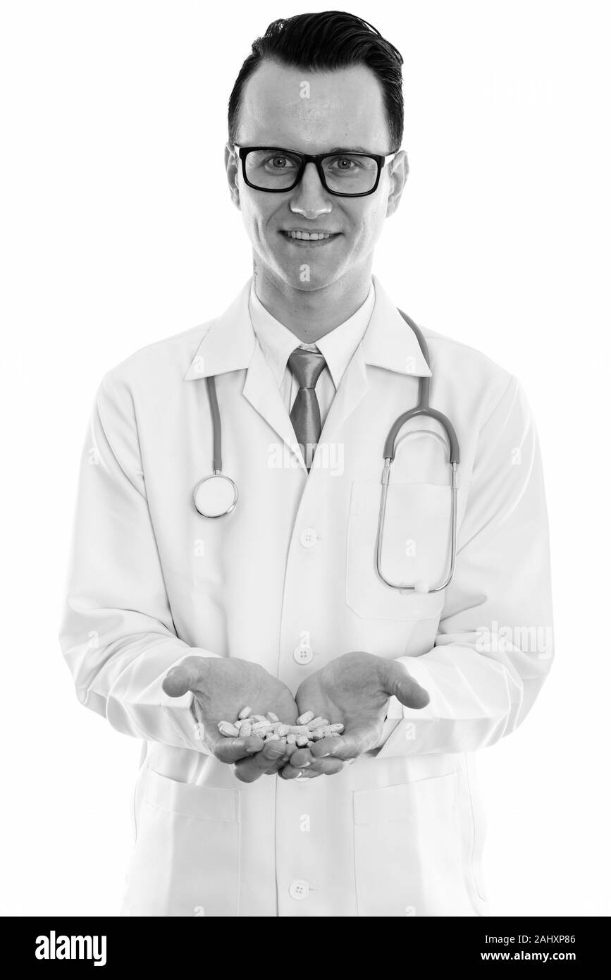 Studio shot of young happy man doctor smiling while holding vitamin tablets with both hands Stock Photo