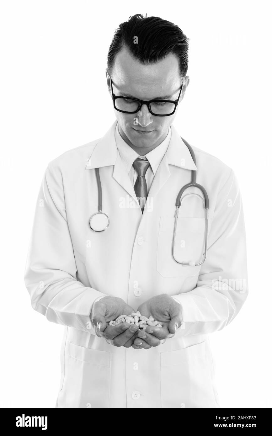 Studio shot of young man doctor holding and looking at vitamin tablets Stock Photo