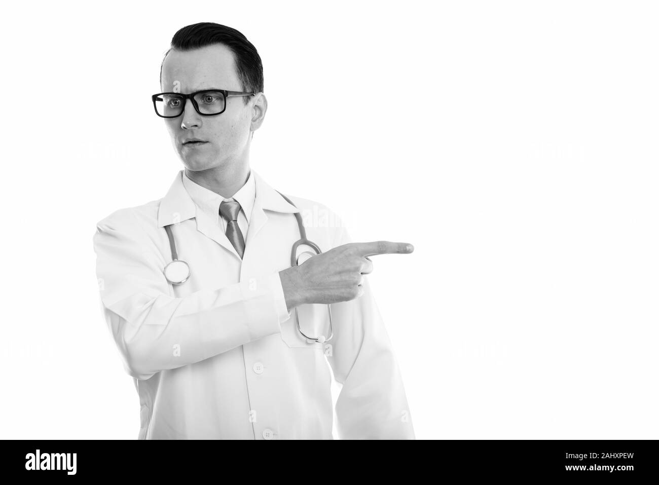 Studio shot of young angry man doctor pointing at side Stock Photo