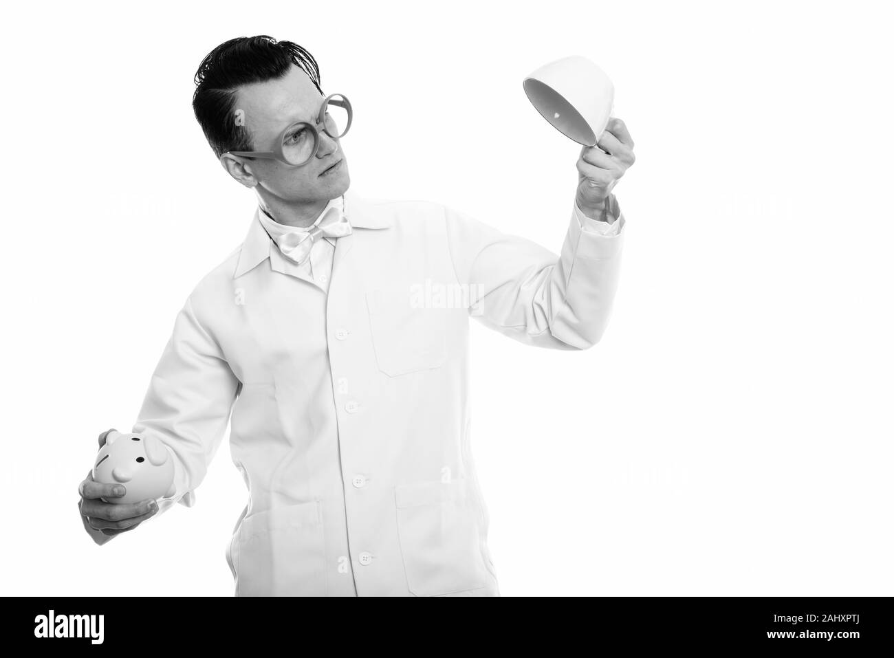 Studio shot of young crazy man doctor holding piggy bank and empty