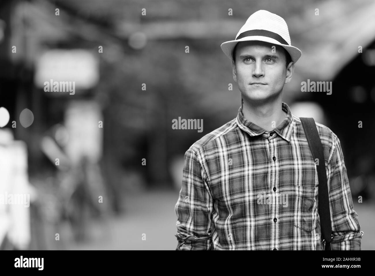 Young handsome tourist man looking at distance while walking at the street market Stock Photo