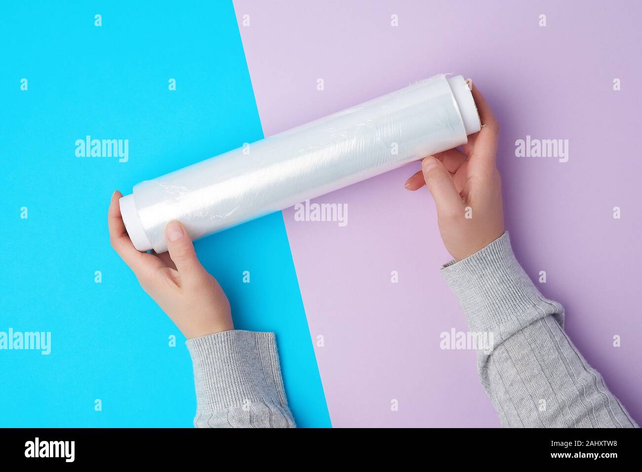 https://c8.alamy.com/comp/2AHXTW8/two-hands-hold-a-large-roll-of-wound-white-transparent-film-for-wrapping-food-top-view-2AHXTW8.jpg