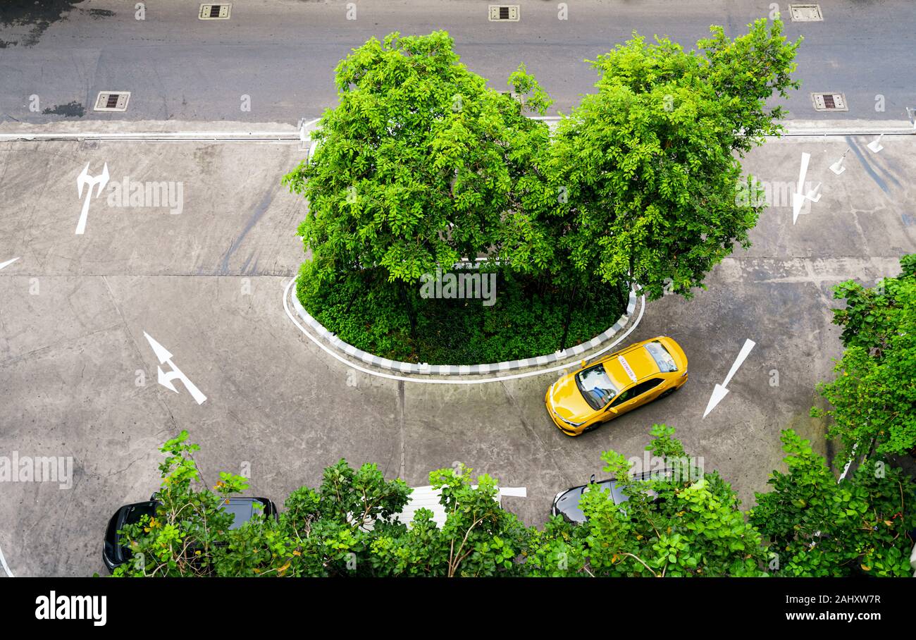 Yellow Thai taxi cab driving in Bangkok city center standing out from the grey asphalt from above. Photograph: Tony Taylor Stock Photo