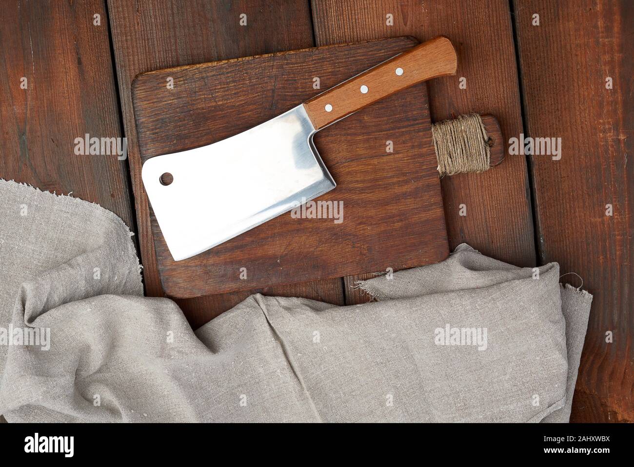 https://c8.alamy.com/comp/2AHXWBX/large-steel-sharp-meat-knife-lies-on-a-rectangular-wooden-brown-board-top-view-2AHXWBX.jpg
