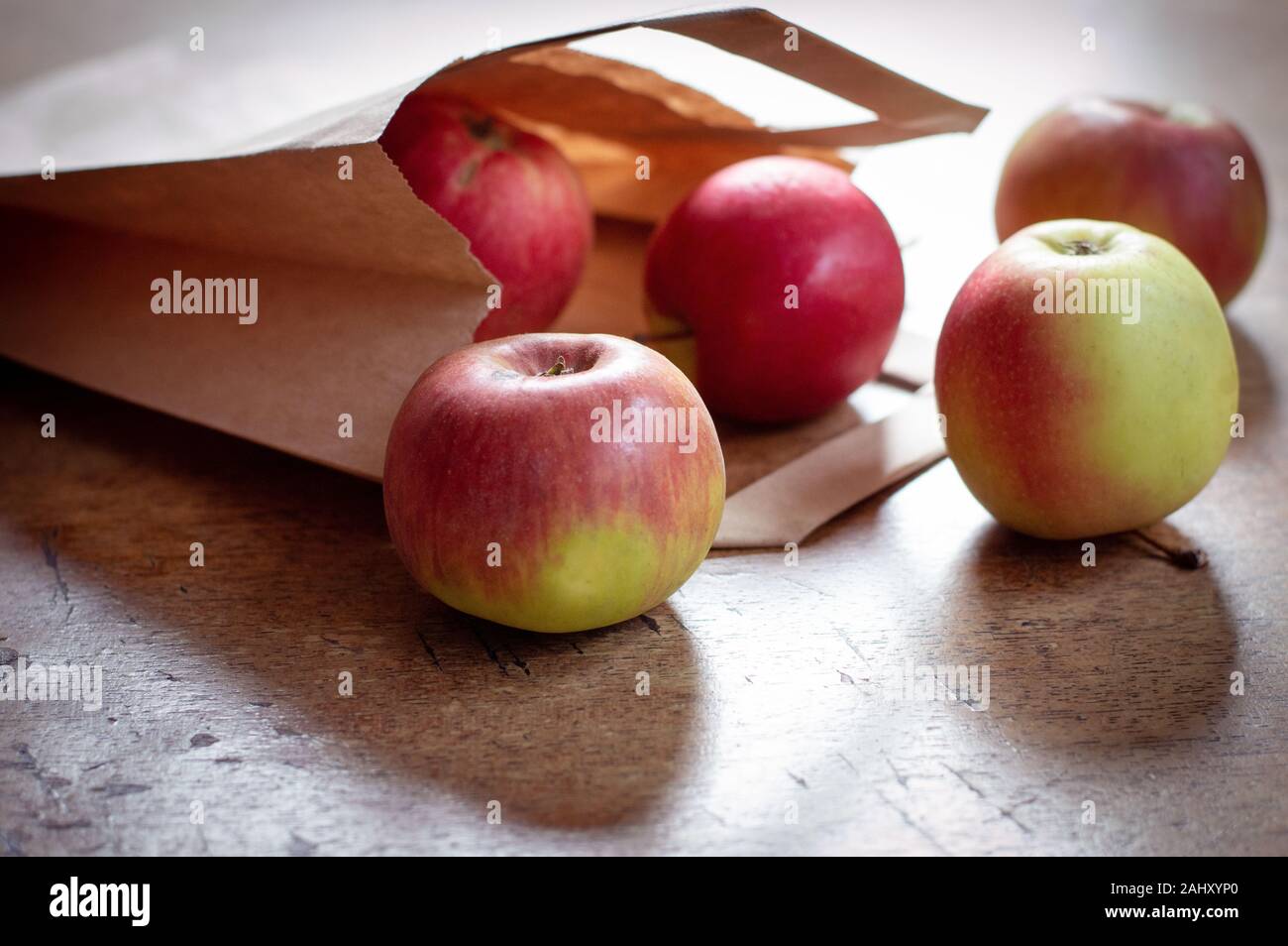 Red healthy apples pouring out of paper shopping bag Stock Photo