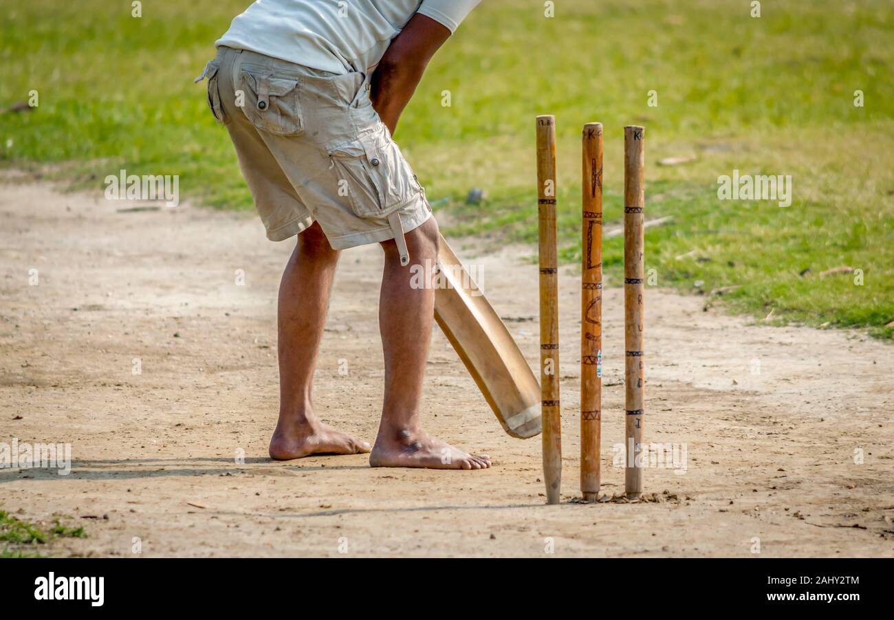 A young Indian boy playing cricket. View of a right handed batsman with all three stumps visible. Stock Photo