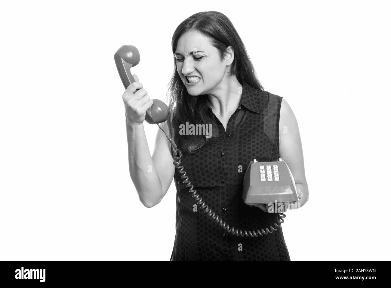 Studio shot of angry woman shouting at old telephone Stock Photo