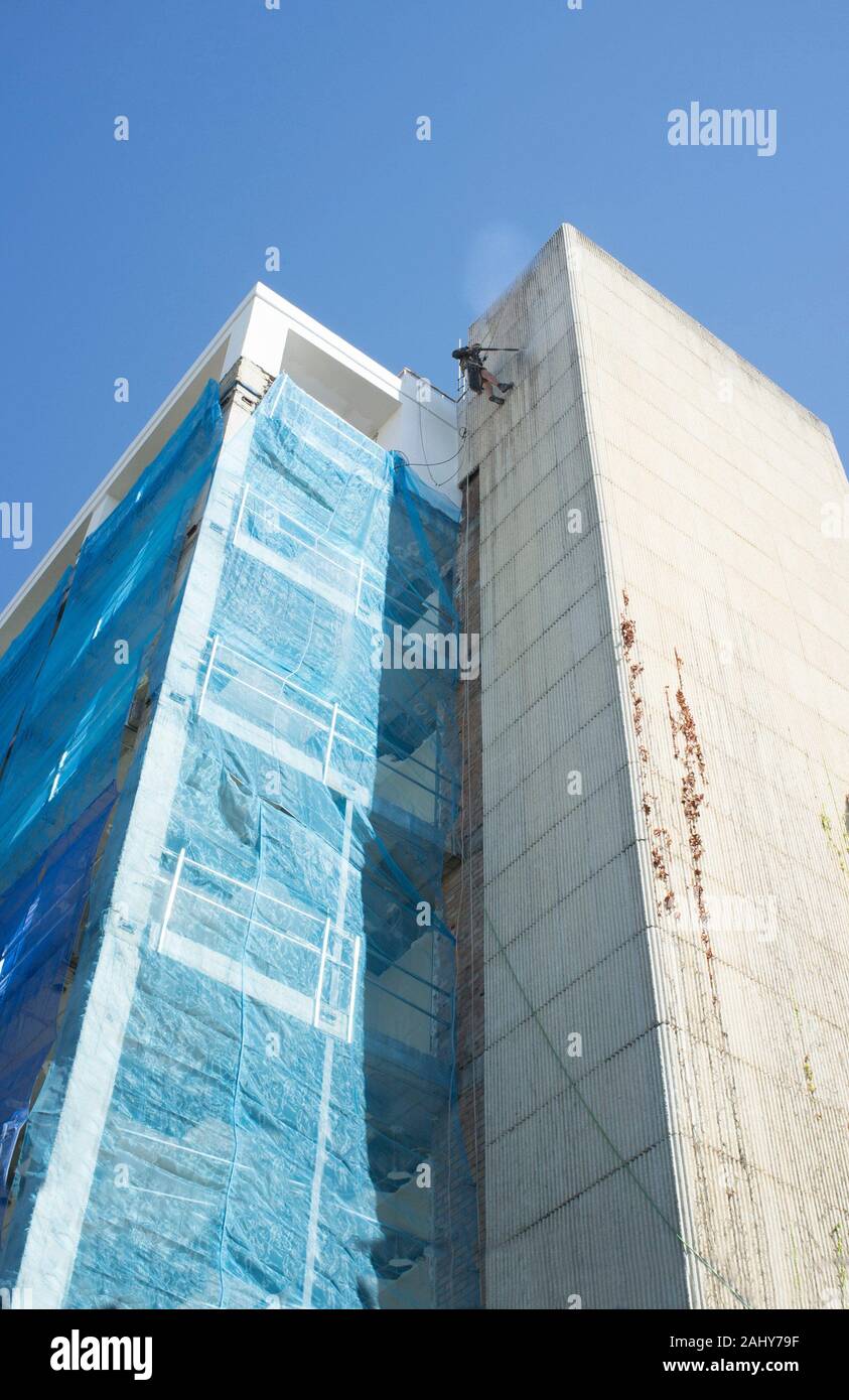 Rope access technician washing building facade. Cleaning service at height concept. Córdoba, Spain Stock Photo