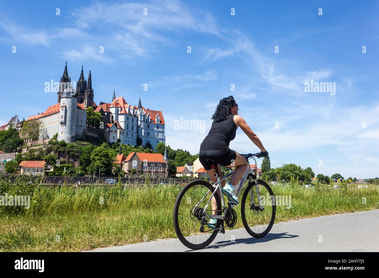 A woman enjoys riding a bike path along the Elbe River Meissen Saxony