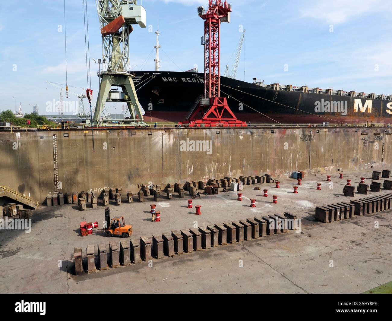 Large oil tanker ship next to a drained dry dock in the port of Antwerp