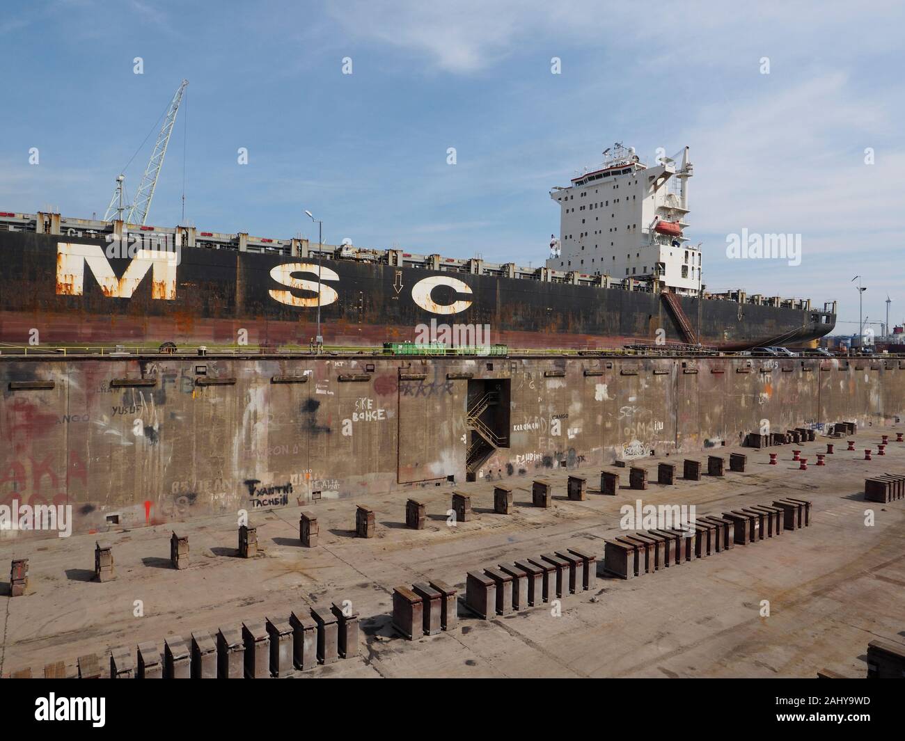 Large oil tanker ship next to a drained dry dock in the port of Antwerp, Belgium Stock Photo