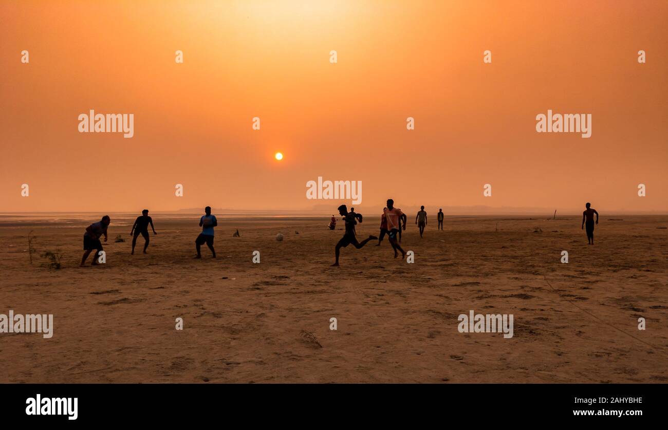 Silhouette Of People , Playing football at the Time of Sunset on a Beach. Stock Photo