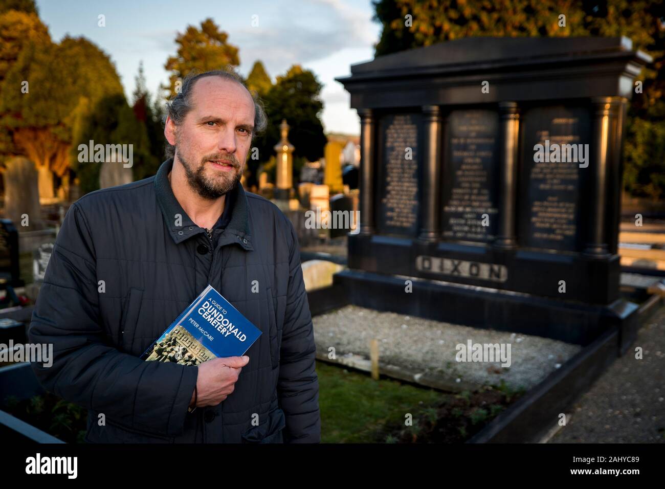 Peter McCabe next to the grave of Sir Thomas & Lady Dixon at Dundonald Cemetery in Belfast, he has unearthed a host of fascinating facts about those who are interred in the east Belfast burial ground of the famous and infamous in his new book. Stock Photo