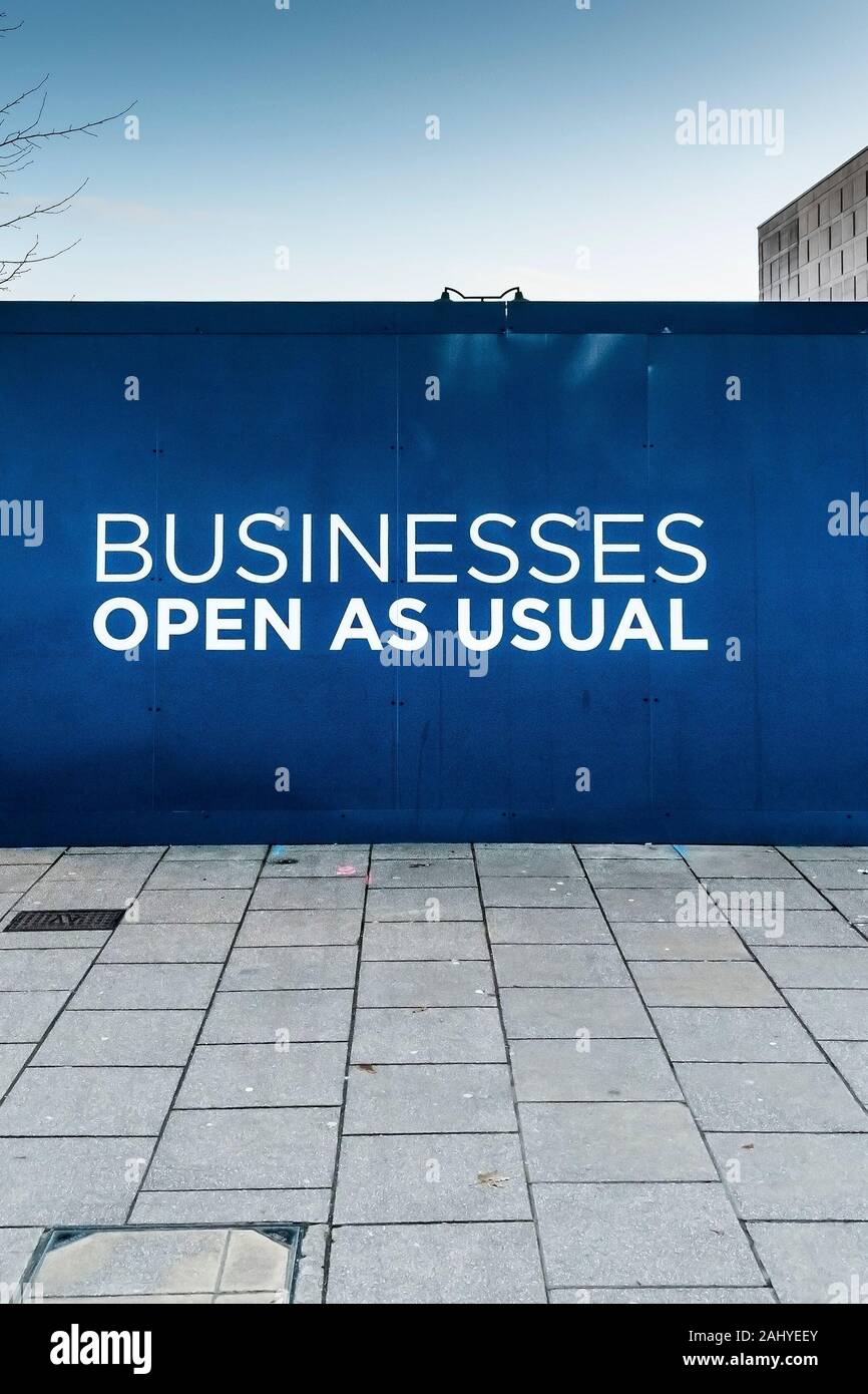 A business as usual sign on a hoarding around a demolition site in Basildon Town centre in Essex. Stock Photo