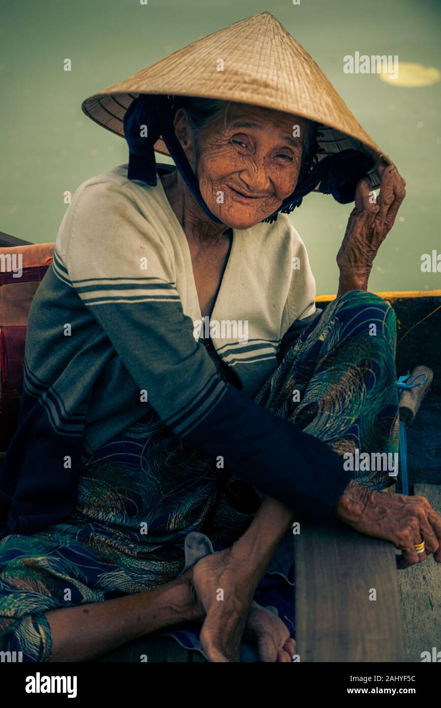 Hoi An, Vietnam. May 05, 2019: Portrait of unidentified old smiling Vietnamese lady in her traditional conical hat. Stock Photo