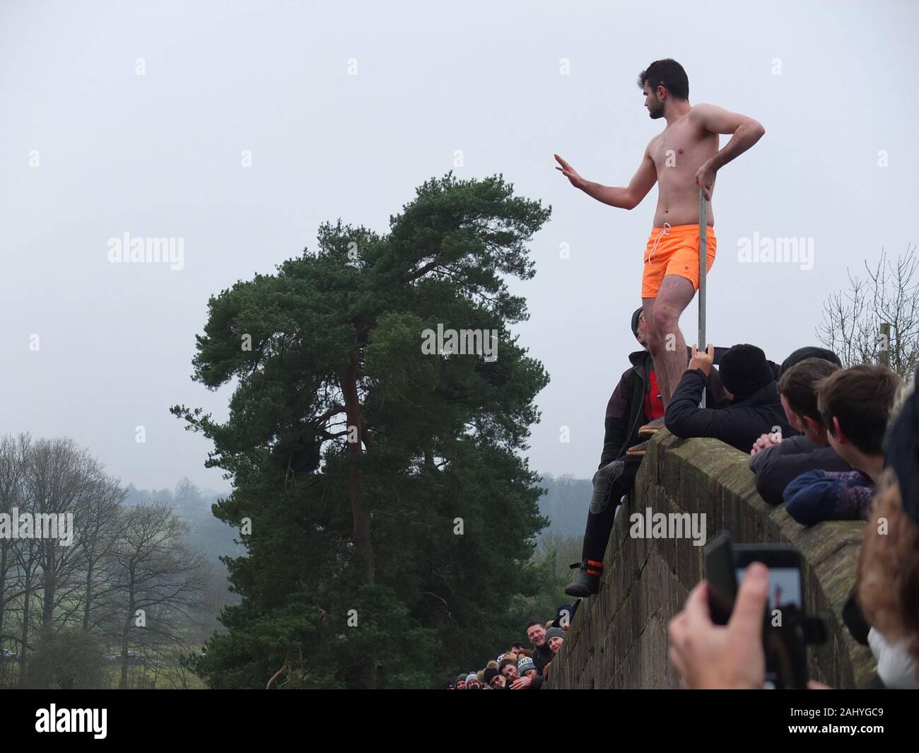 Mappleton (Mapleton) Bridge Jump, annual New Years Day custom. Participant in swimming trunks prepares to jump off Okeover Bridge and into River Dove. Stock Photo