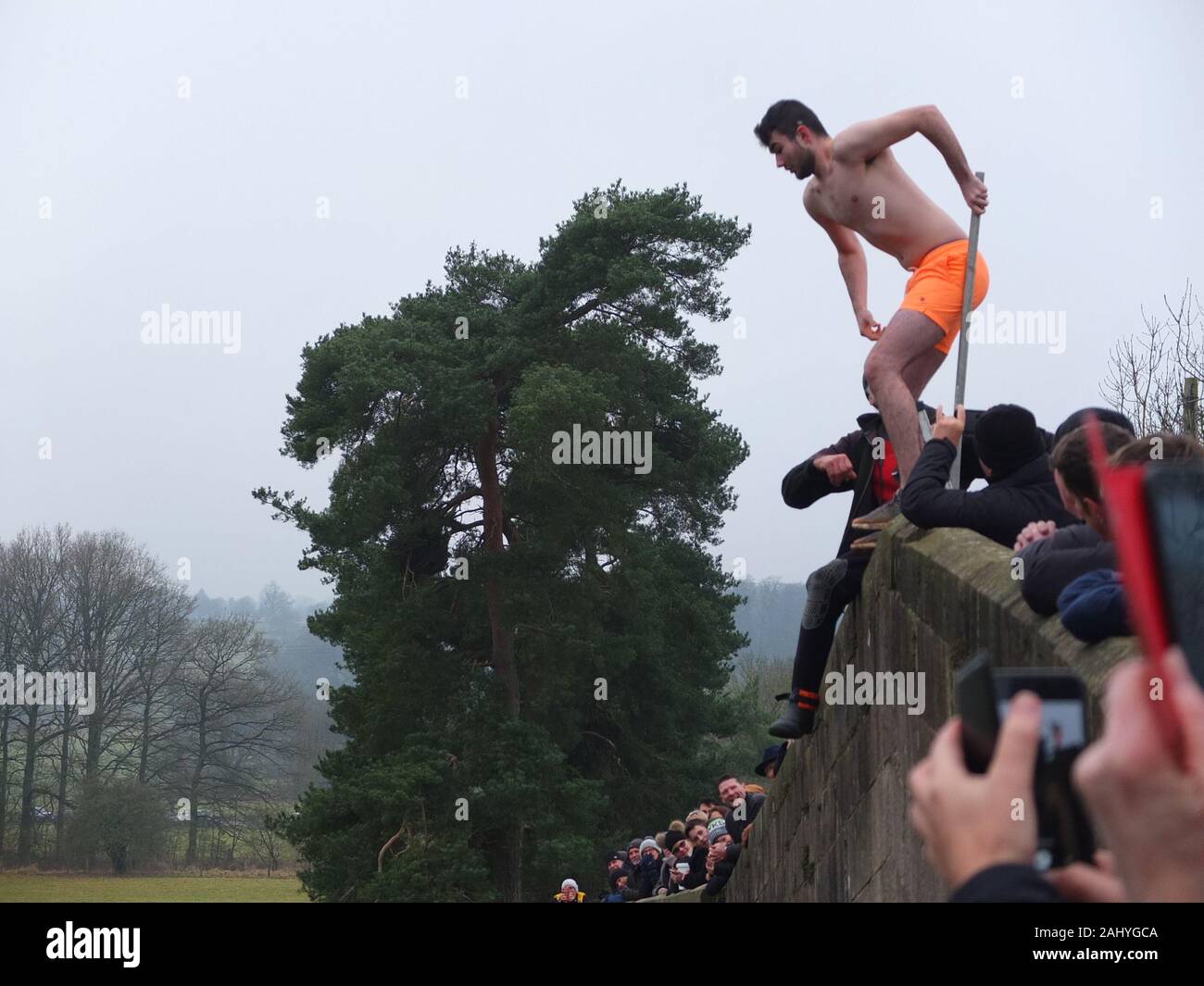 Mappleton (Mapleton) Bridge Jump, annual New Years Day custom. Participant in swimming trunks prepares to jump off Okeover Bridge and into River Dove. Stock Photo