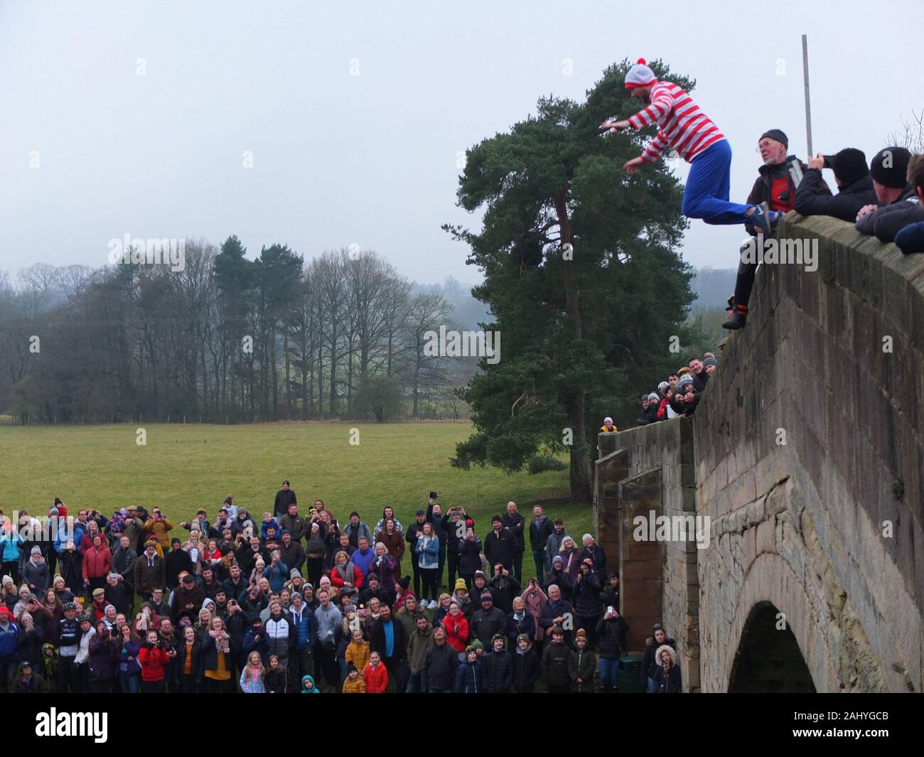 Mappleton (or Mapleton) Bridge Jump, annual New Years Day custom. Participant dressed as Where's Wally jumps off Okeover Bridge and into River Dove. Stock Photo