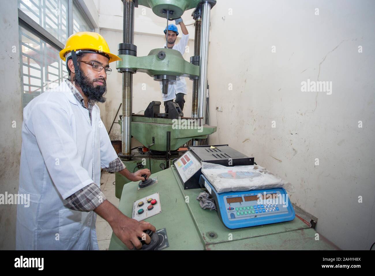 Bangladesh.A factory lab operator using Steel rod strength testing