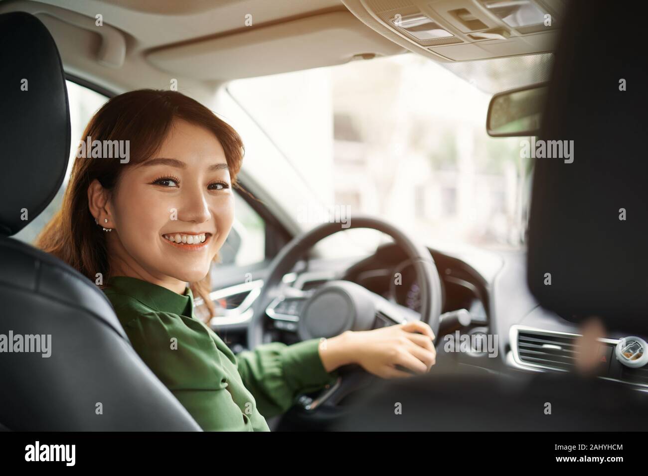 Confident and beautiful. Rear view of attractive young woman in casual wear looking over her shoulder while driving a car Stock Photo