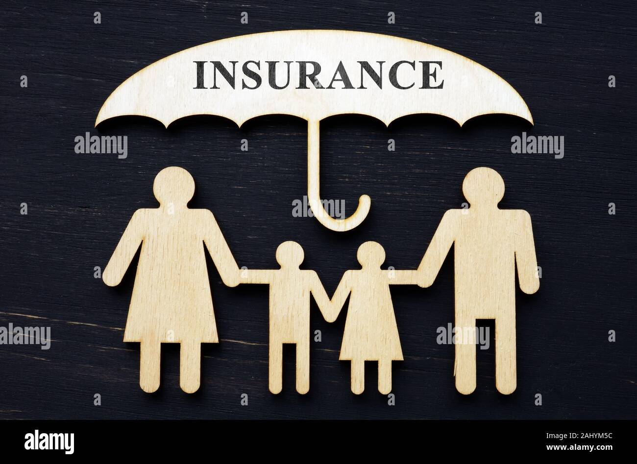 Life insurance concept. Figurines of a family under an umbrella. Stock Photo