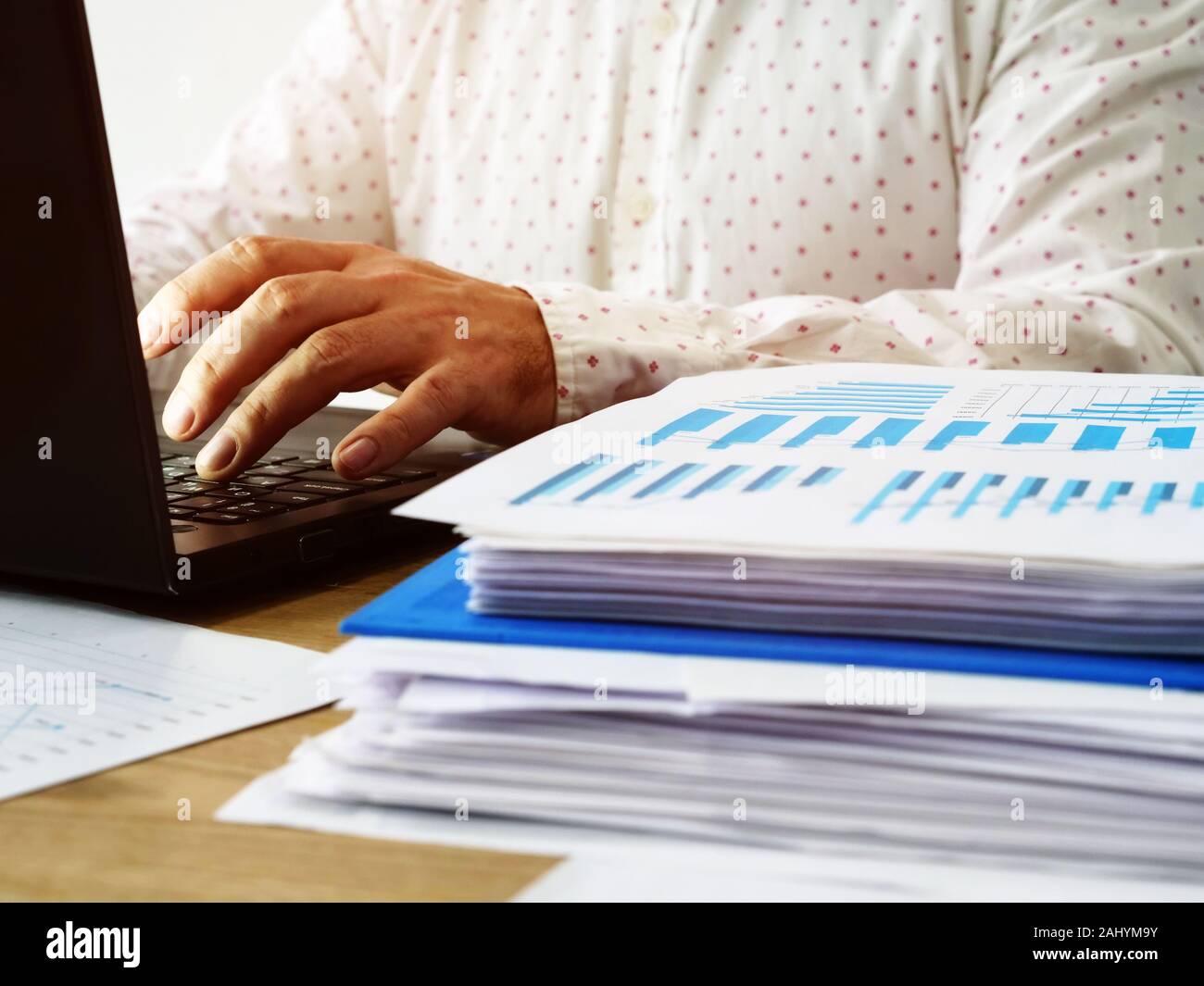 A young man is typing on a laptop keyboard in an office. Annual report writing. Stock Photo