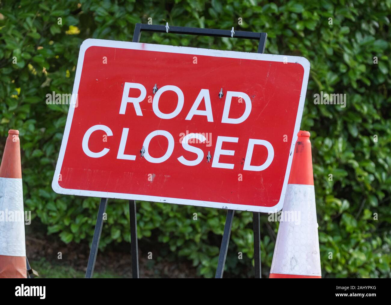 A red road closure sign (UK) in the middle of red and white traffic cones. Stock Photo