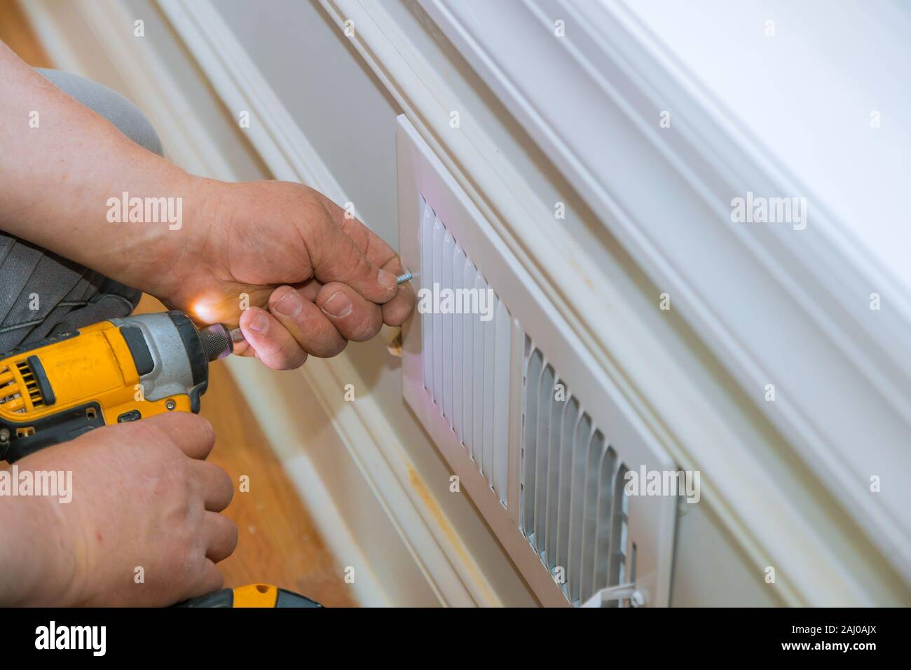 Maintenance repair, man is making the wall vent cover indoor central air conditioning, vents Stock Photo