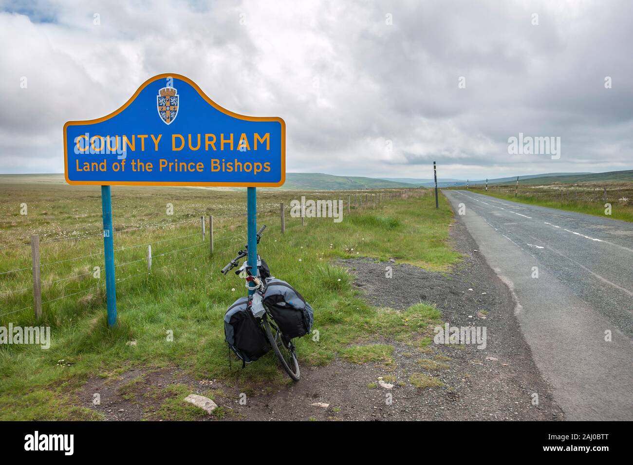 COUNTY DURHAM, ENGLAND - JUNE 15, 2016 - A touring bike leaning against a sign post on the border of County Durham, northern England Stock Photo
