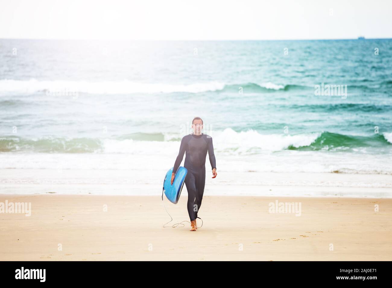 Man walk with surfboard from the sea on a beach Stock Photo - Alamy