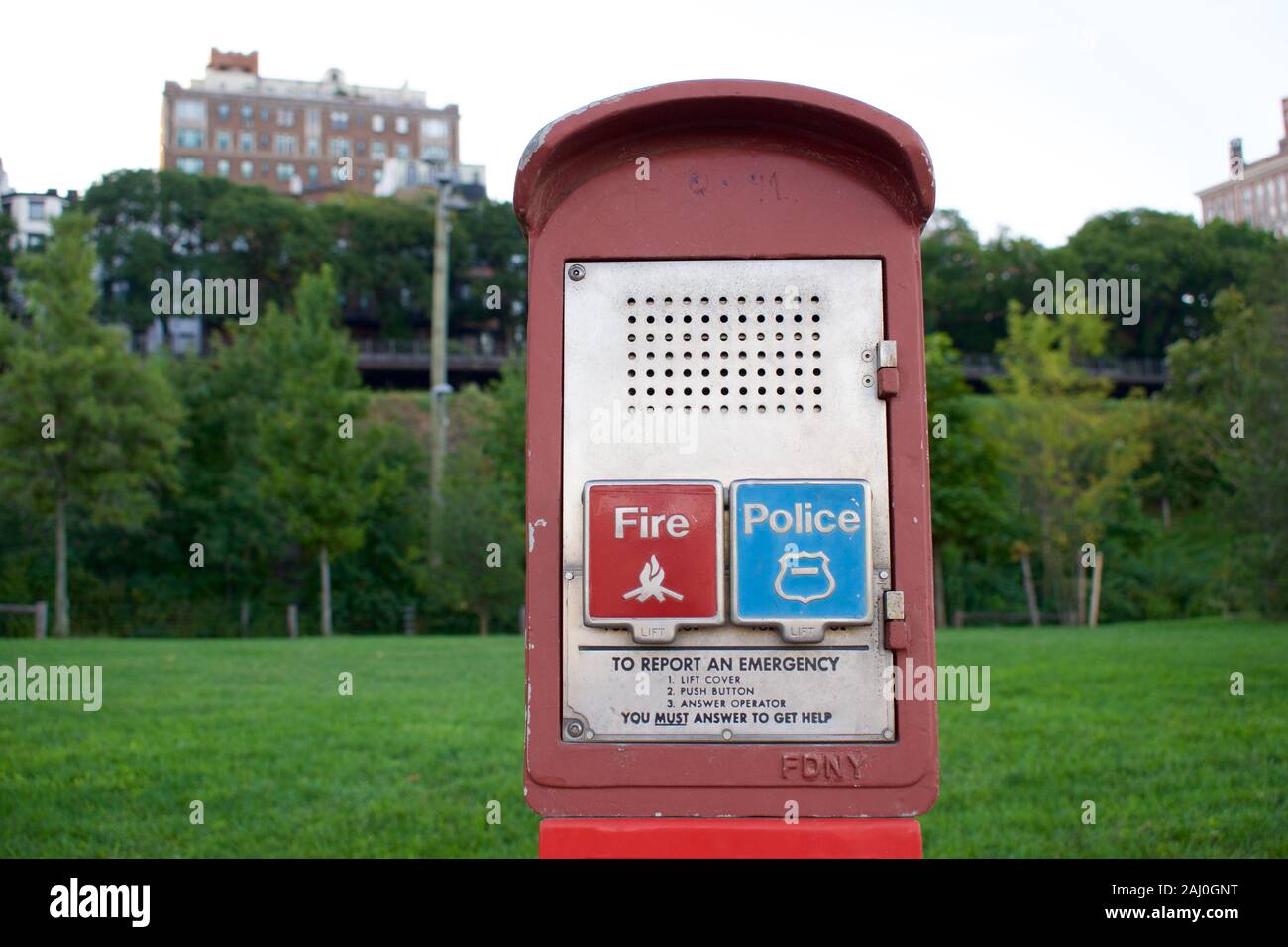 An emergency police and fire call box in New York City. A red metal box with a red flap covering red button for FDNY and a blue button for NYPD. Stock Photo
