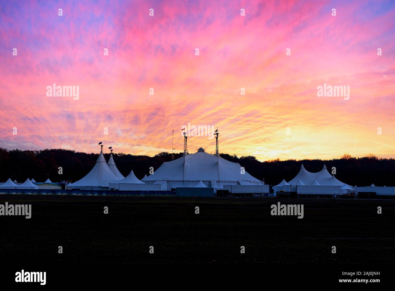 Circus tent under a warn sunset and chaotic sky without the name of the circus company which is cloned out and replaced by the metallic structure Stock Photo