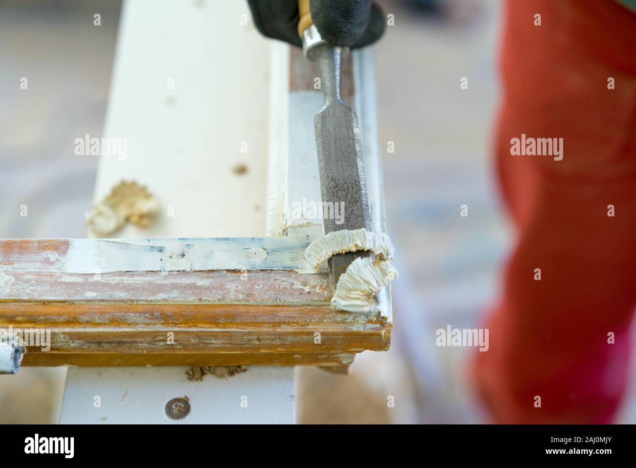 Man removes old paint on a wood window Stock Photo