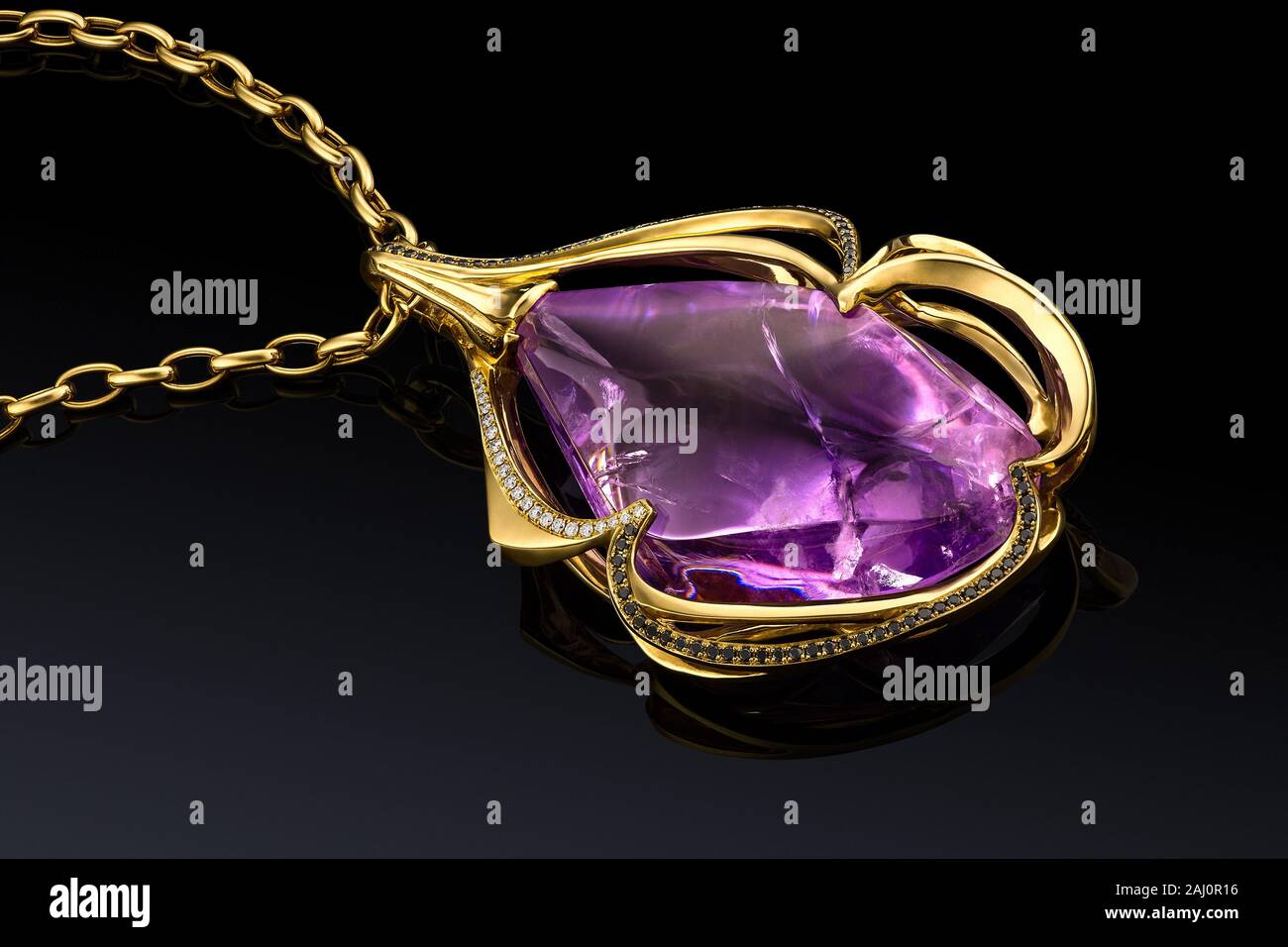 luxury yellow gold pendant with amethyst and diamonds isolated on black background with reflection, included clipping path. extreme close up. Stock Photo