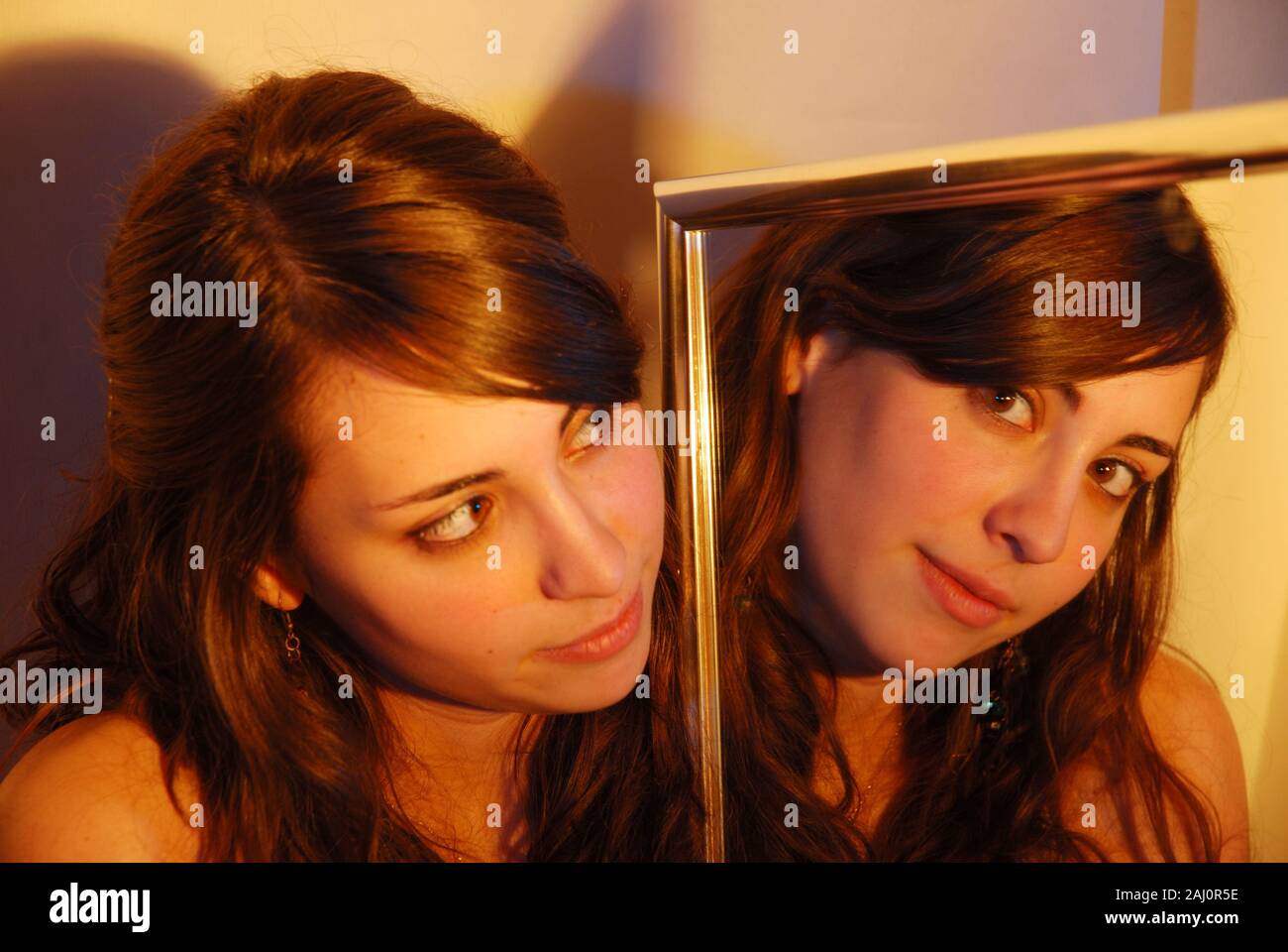 Young woman looking at the camera from her reflection on a mirror. Stock Photo