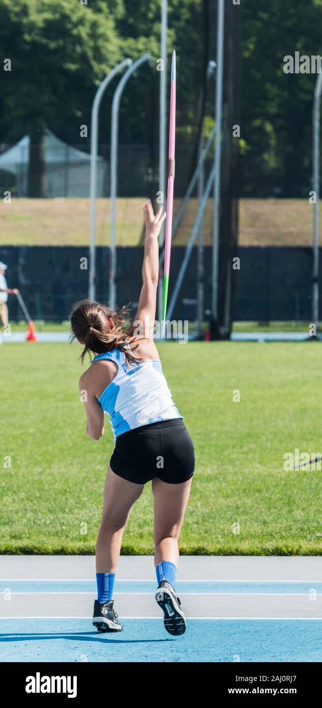 A high school girl track and field athlete is throwing a javelin during