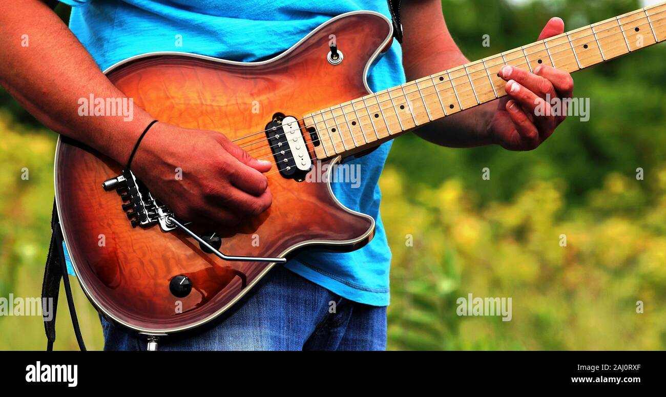 Close up of hands playing an electric guitar while outside. Stock Photo