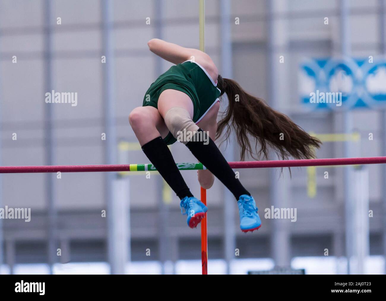 A high school girl is clearing the bar during a pole vault competition at a track meet. Stock Photo