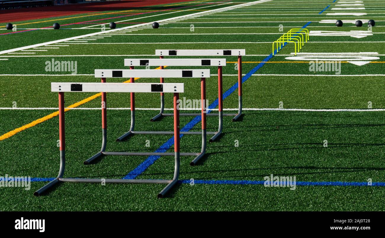 A green turf football field has hurdles and medicine balls set up for strength, speed and agility practice. Stock Photo
