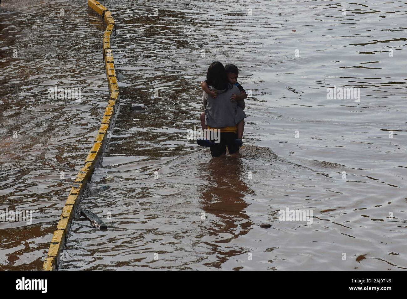 Jakarta, Indonesia. 2nd Jan, 2020. A mother holds her son in her arms while wading through flood water in Jakarta, Indonesia, Jan. 2, 2020. In Jakarta, evacuation of the flood-affected persons persisted as waters still submerged several parts of the city, and six people were reported dead in the city, said M. Ridwan, spokesman for a disaster agency in Jakarta. Credit: Agung Kuncahya B./Xinhua/Alamy Live News Stock Photo