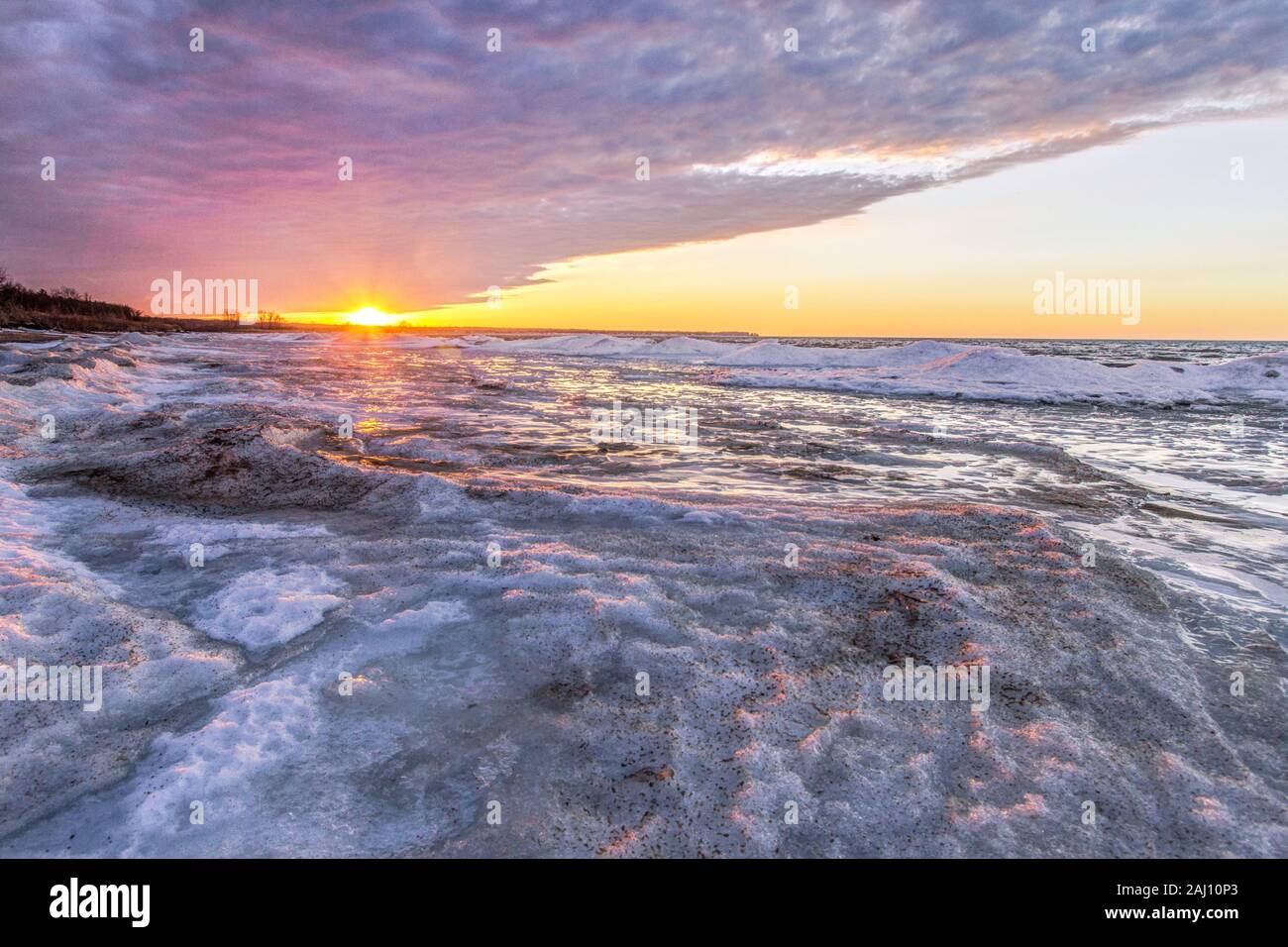 Michigan Winter Lake Landscape.  Rays of sun illuminate the frozen icy coast of Lake Huron Michigan on the Great Lakes Coast. Stock Photo