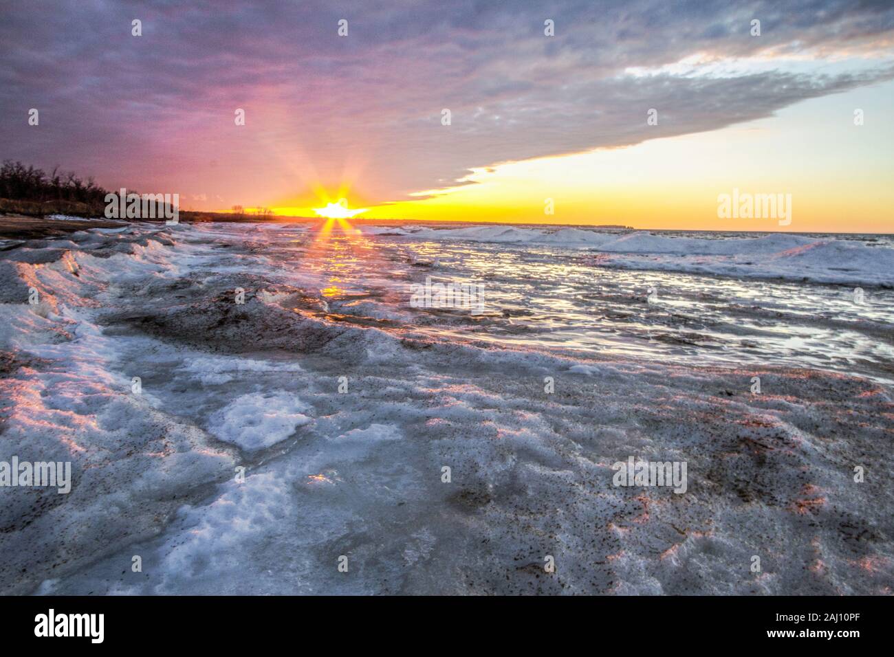 Michigan Winter Lake Landscape.  Rays of sun illuminate the frozen icy coast of Lake Huron Michigan on the Great Lakes Coast. Stock Photo
