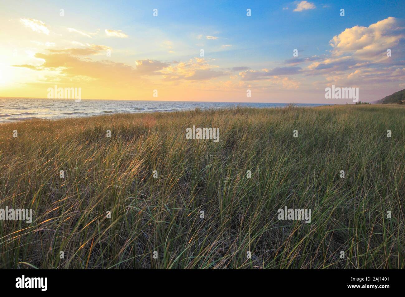 Summer Sunset Beach Background. Beautiful summer sunset on the Lake Michigan coast with dune grass in the foreground at Hoffmaster State Park. Stock Photo