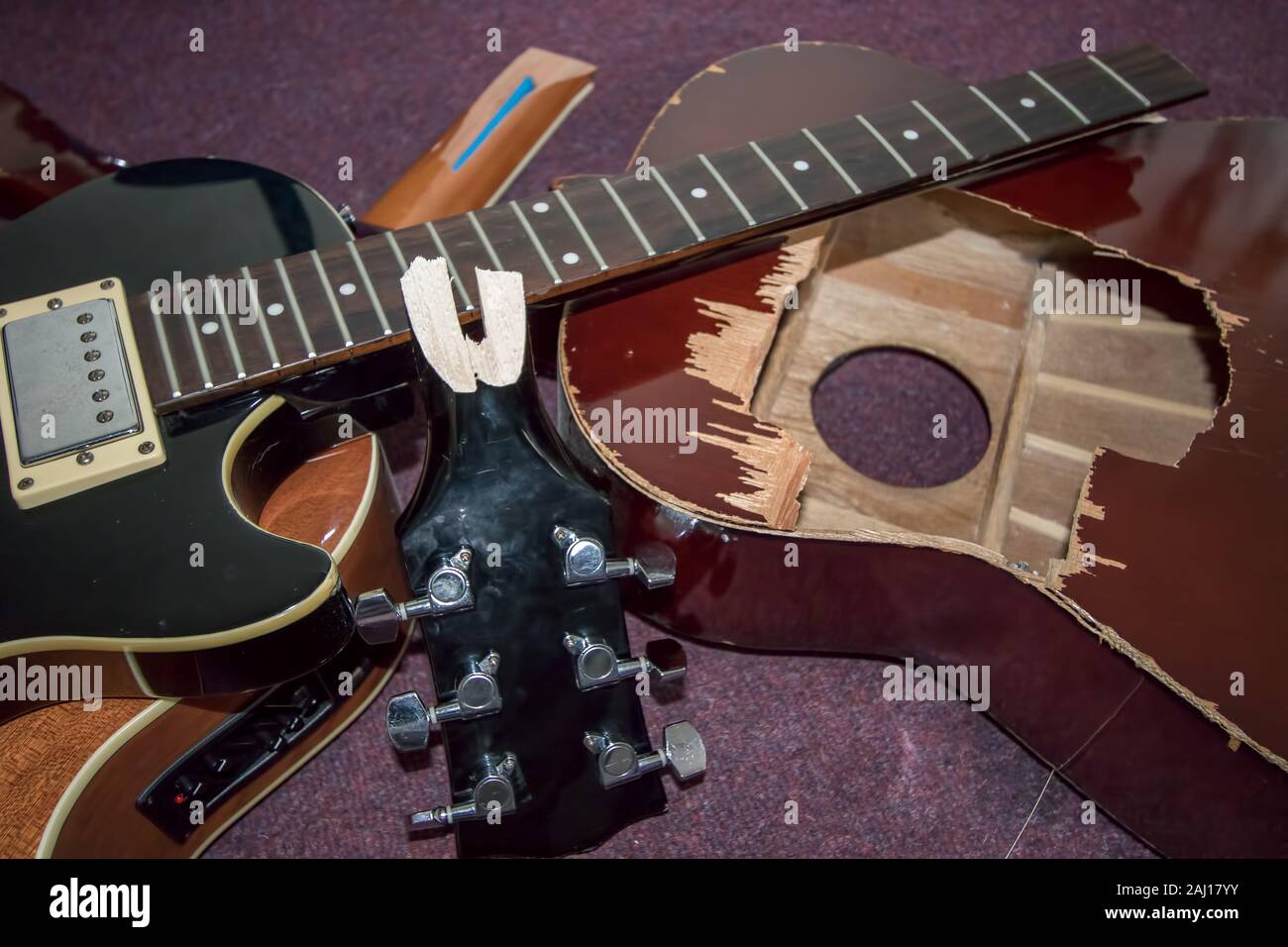 Broken guitars. Pile of smashed electric and acoustic guitar pieces. Frustrated guitarist smashed instrument parts ready for burning or repair. Stock Photo
