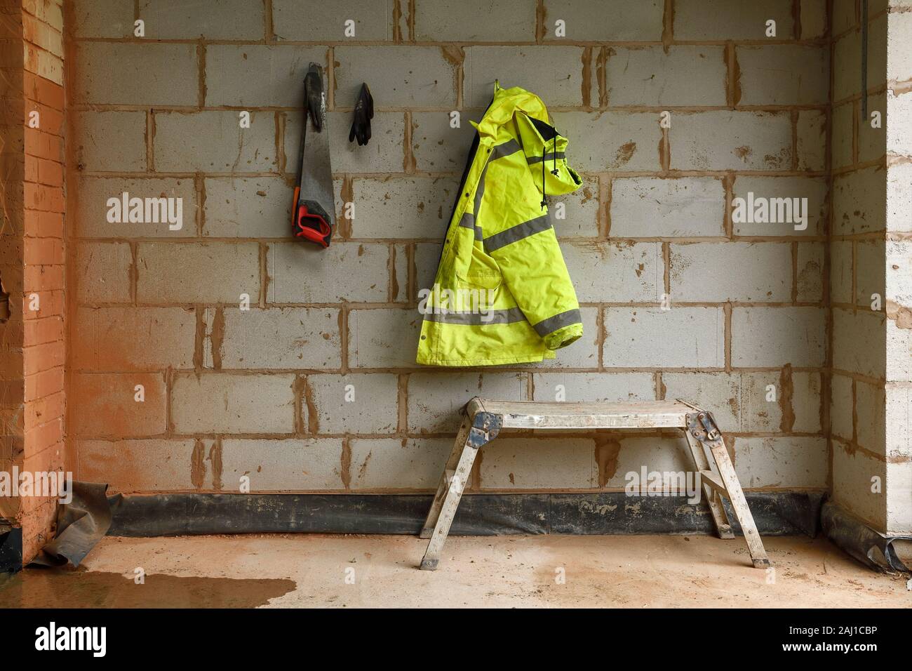 A coat and saw hanging on nails at a building site in the UK Stock Photo